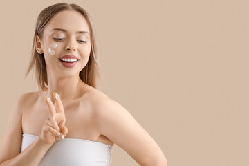 Wall Mural - Pretty young woman with cream on her face against beige background