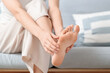 © Pixel-Shot - Young woman with flat feet doing massage on sofa at home, closeup