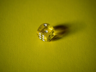 Slick dice on yellow paper background. Cardboard bright background with texture. Concept of luck, testing fate, lottery, decision making. Place for text. Copy space. Rovinj, Croatia - October 4, 2024