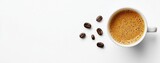 Overhead view of frothy espresso cup surrounded by coffee beans on white background, aromatic