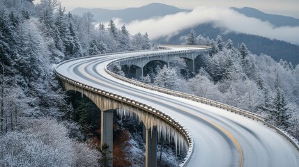 Wall Mural - Snowy winter landscape featuring a stone bridge over a winding road in a forest setting