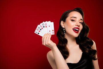 Stunning happy lady poker gamer showing cards winning million isolated on red color background