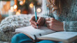 © Valeriia - Woman writes her thoughts in the diary notebook with a pen with Christmas bokeh lights on background. Wish list, New Year resolutions concept