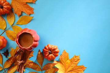 Wall Mural - Autumn fall leaves, cinnamon sticks, cup of coffee on blue background. Flat lay, top view, copy space.
