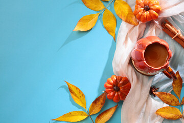 Wall Mural - Autumn composition. Flat lay feminine scarf, cup of coffee, cinnamon sticks, pumpkins, branches with yellow leaves on blue background. Top view with copy space
