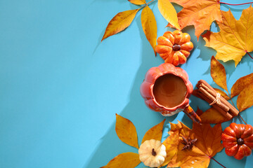 Wall Mural - Autumn flat lay composition. Top view cup of coffee, pumpkins, cinnamon sticks, yellow leaves branches on blue background. Autum, Fall, Thanksgiving concept.
