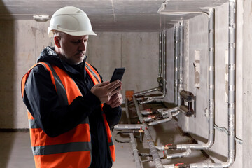 Poster - man engineer near heating pipes. construction worker in basement with insulated pipeline. man with p