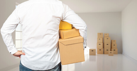 Relocation process. Man makes move. Guy with boxes in empty room. Person is engaged in relocation. Homeowner with boxes back to camera. Relocation to new housing. Carrying things while moving