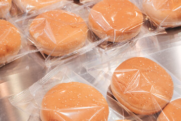 Poster - A row of hot dogs are wrapped in plastic. The hot dogs are all the same size and shape