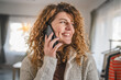 © Miljan Živković - woman with curly hair at home use mobile phone smartphone have a call