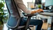 © IMAGINIAC - Close-up of a person sitting in an office chair using a computer mouse