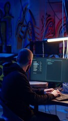 Poster - vertical video hacker in underground warehouse writing lines of code on computer screen to make malw