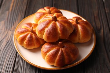 Wall Mural - Tasty pumpkin shaped buns on wooden table, closeup