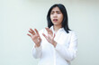 © M Alfan Setyawan - portrait of shocked asian business woman reaching hands towards camera looking away confused and afraid wearing white shirt formal suit standing isolated background