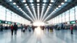 © narak0rn - Blurred view of a busy airport terminal filled with travelers and bright lighting.