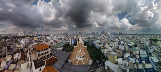 French Colonial Church and Ho Chi Minh City Skyline panorama View of high density urban area aerial rooftop view with dramatic sky.