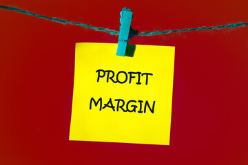 Business and financial concept. PROFIT MARGIN words. text written on a yellow sticker on a rope in front of a red background