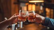 © Malay - Cheers to Friendship. Two Men Clinking Whiskey Glasses at a Bar, Warm Lighting, Rustic Décor, and Lively Atmosphere