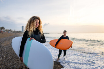 Two happy young surfers with surfboard prepares to hit the waves at sunset. Sports active vacation