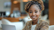 © visoot - African corporate professional female internal audit manager in office seated in office chair working, happy and smiling, formal professional hairstyle and formal attire, laptop on table.