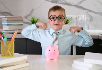 Happy and excited child in shirt and tie makes victorious gesture. Smart businessman boy with piggy bank. Business school, investing and financial education for children. 