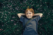 © Westend61 - Smiling boy with hands behind head lying on grass
