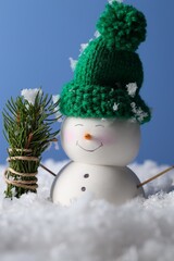 Wall Mural - Cute decorative snowman and fir tree branches on artificial snow against light blue background, closeup