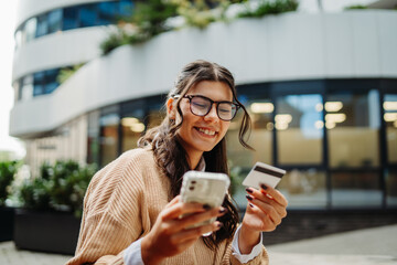 Young caucasian woman using credit card to buy online on her phone	