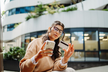 Young caucasian woman using credit card to buy online on her phone	