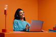 © Jacob Lund - Customer service agent working with a laptop in orange monochromatic office