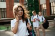 © standret - Girl is talking by phone. Kids are near the school together, pupils