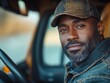 © julija - dedicated black male truck driver behind the wheel of a cargo truck, exuding determination and professionalism as he navigates the open road. captures the essence of the transport industry