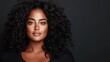© Maximages  - A woman with voluminous curly hair and natural makeup poses against a dark backdrop, exuding confidence and elegance in a black off-the-shoulder top.