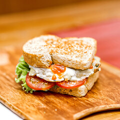 SANDWICH WITH HAM Lettuce and tomato on a wooden tray