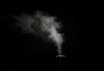 Leinwandbilder - White wispy smoke rises from the top of a dark object against a black background.