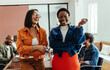 © (JLco) Julia Amaral - Young women colleagues laughing and enjoying a vibrant and colorful workplace in a creative boardroom