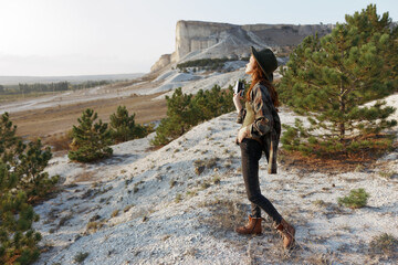 Wall Mural - Woman standing on hill admiring majestic mountain and lush valley with pine trees in background