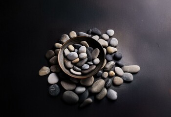 Poster - A wooden bowl filled with gray, black and white smooth stones on a dark gray background.