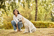 © LIGHTFIELD STUDIOS - The woman in warm autumn attire smiles while spending joyful moments outdoors with her dog.