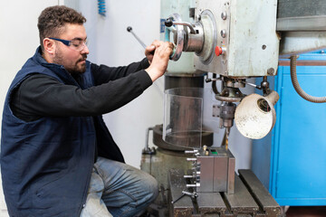 Lathe worker man working with a vernier and milling machine in a factory, using a caliper to check measurement.