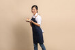 © PBXStudio - Beautiful and attractive Asian female coffee shop owner wearing apron, casual clothes. She holds a cake in her hand, smiling brightly on beige background.