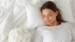 © DuangphonKPR - A serene woman peacefully sleeps on a soft bed with pillows, surrounded by a calming atmosphere and delicate flowers.