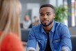 © SerPak - A young man with a beard wearing a denim shirt is sitting in an office environment, attentively listening to a conversation or presentation, looking engaged and focused.