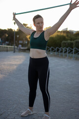 Wall Mural - Athletic woman doing arm workout with resistance band outdoors