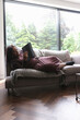© Caia Image - Disabled woman lying with tablet on sofa