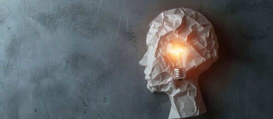 Wall Mural - Business idea illustrated by a paper human head with a light bulb on a grey background with copy space image