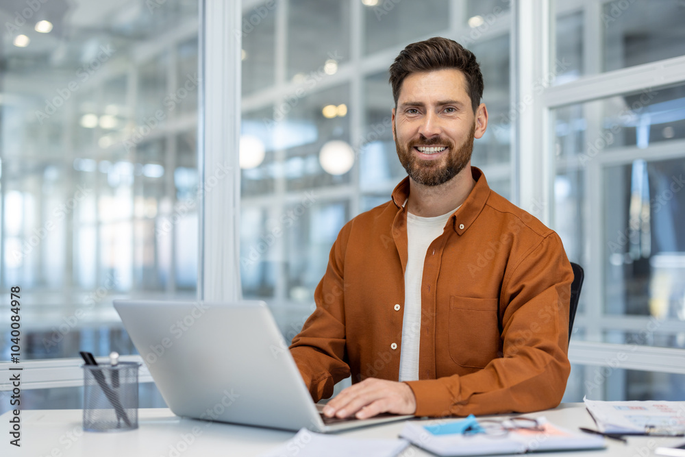 Confident professional man with a smile working on laptop in modern ...