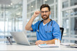 © Liubomir - Smiling healthcare professional in blue medical scrubs at modern office with laptop. Stethoscope around neck, adjusting glasses, conveying professionalism, warmth, competence
