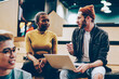 © BullRun - Young hipster guy with laptop computer having conversation with african american colleague planning homework project, crew of multiracial coworkers having consultancy share ideas with each other