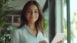 © Johannes - Portrait of young Hispanic professional business woman standing in office. Happy female company executive, smiling businesswoman entrepreneur corporate leader manager looking at camera using tablet